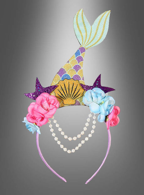 Wir präsentieren den „Meerjungfrau“-Haarreif – ein verspieltes Stirnband, verziert mit einer glitzernden Meerjungfrauenflosse, einer Muschel, einem violetten Seestern, rosa und blauen Blumen sowie zwei Perlenketten auf grauem Grund. Perfekt als Meerjungfrauen-Kinderkostüm oder als bezauberndes Meerjungfrauen-Accessoire zum Verkleiden und für fantasievolles Spielen.