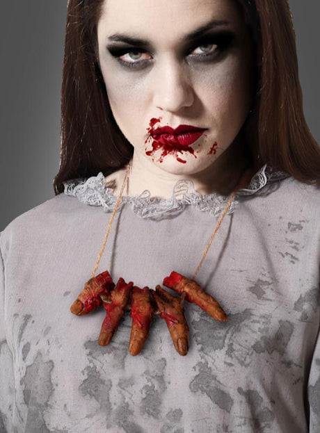 Eine Frau mit verschmiertem dunklem Make-up und Blutspuren um den Mund trägt die Halloween-Halskette „Abgehackte Finger“ als auffälliges Halloween-Accessoire, kombiniert mit einem fleckigen grauen Oberteil, vor einem neutralen Hintergrund.
