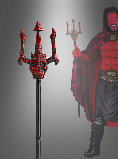 Eine Person in einem rot-schwarzen Teufelskostüm hält einen roten Dreizack mit Teufelsgesicht (110 cm) in der Hand, der im Vordergrund im Detail zu sehen ist.