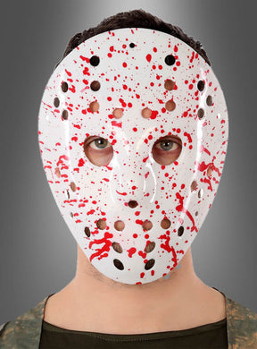 Eine Person trägt die blutbespritzte Eishockeymaske und blickt vor einem schlichten grauen Hintergrund nach vorne. Diese weiße Horrormaske ist mit leuchtend roten Spritzmustern verziert, die für einen unverkennbar gruseligen Effekt sorgen.