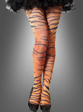 Ein Model präsentiert die Strumpfhose mit Tigermuster und kombiniert die Strumpfhose mit Tigermuster mit schwarzen High Heels, während sie mit gekreuzten Beinen vor einem schlichten grauen Hintergrund steht.