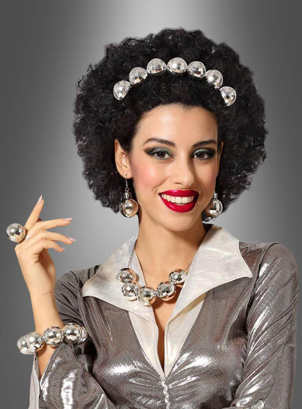 Eine Frau mit lockigem schwarzem Haar, gekleidet in ein glänzendes silbernes Outfit und mit funkelndem Schmuck aus dem „Silbernes Discokugel“-Schmuckset, lächelt vor einem grauen Farbverlaufshintergrund – ideal für jede 80er-Party.
