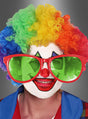 Eine Person mit einer Regenbogenperücke, einer roten Nase und einer übergroßen roten „Riesenbrille für Clowns“-Sonnenbrille, mit weißer Gesichtsbemalung und buntem Clown-Make-up, gekleidet in ein blau-rotes Kostüm, lächelt in die Kamera – bereit, auf jeder Schlagerparty für gute Laune zu sorgen.