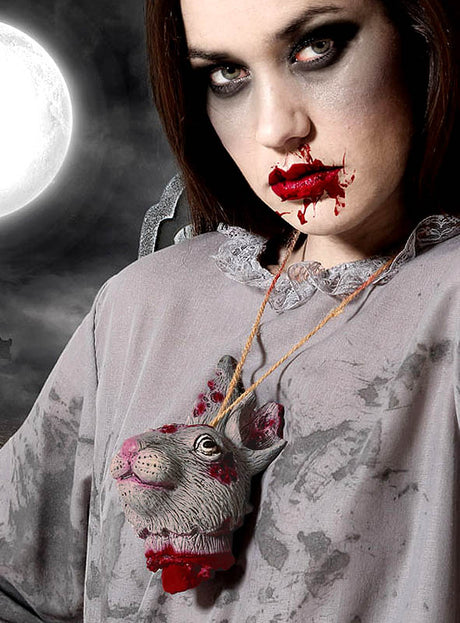 Eine Frau mit Blut im Gesicht trägt die „Hasenkopf Zombie Kette Halloween“ – eine Halskette, die mit einem abgetrennten Kaninchenkopf verziert ist – und verleiht ihrer Halloween-Dekoration damit einen unheimlich unverwechselbaren Touch. Vor dem Hintergrund dunkler Wolken und eines bedrohlich aufgehenden Vollmonds wird die Spannung in dieser eindrucksvollen Präsentation von Zombie-Kostümzubehör noch verstärkt.
