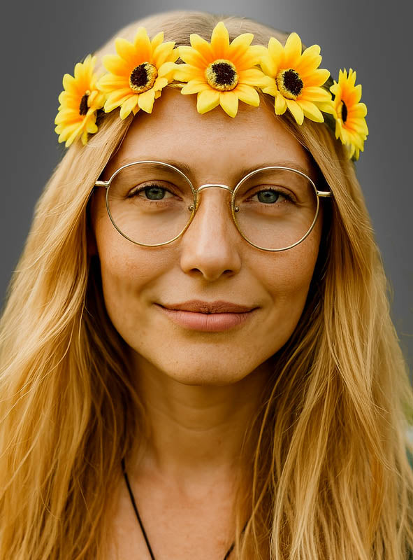 Eine Person mit langen blonden Haaren trägt eine runde Brille und einen gelben Sonnenblumen-Haarkranz für Hippies, was an einen klassischen Damenanzug erinnert, und blickt vor einem schlichten Hintergrund in die Kamera.