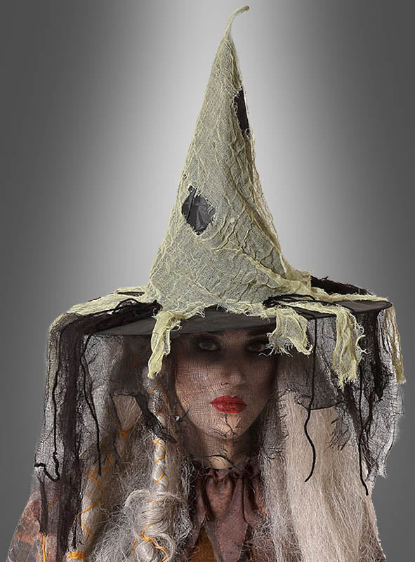 Eine Person, die einen zerfetzten, spitzen „Fetziger Hexenhut Deluxe“ in Grau-Schwarz mit ausgefranstem Netzstoff und dunklem Make-up trägt und vor einem grauen Hintergrund mit Farbverlauf steht – eine bezaubernde Note für jedes Waldhexe-Kostüm.