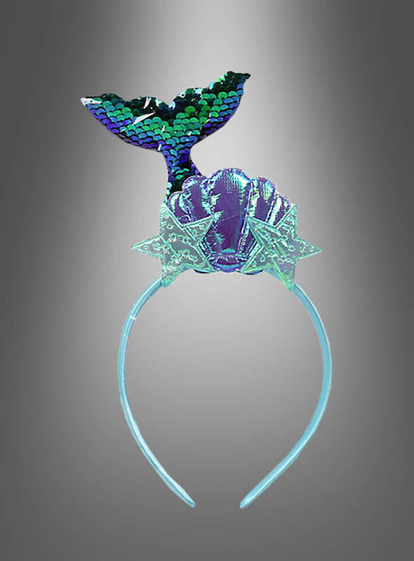 Wir präsentieren den Haarschmuck „Meerjungfrau“: ein funkelndes Haarschmuckstück, verziert mit einem blauen Meerjungfrauen-Schwanz, einer violetten Muschel und zwei glitzernden Seestern-Verzierungen – perfekt, um dein zauberhaftes Meerjungfrau-Kostüm zu vervollständigen. Präsentiert vor einem eleganten grauen Hintergrund mit Farbverlauf.