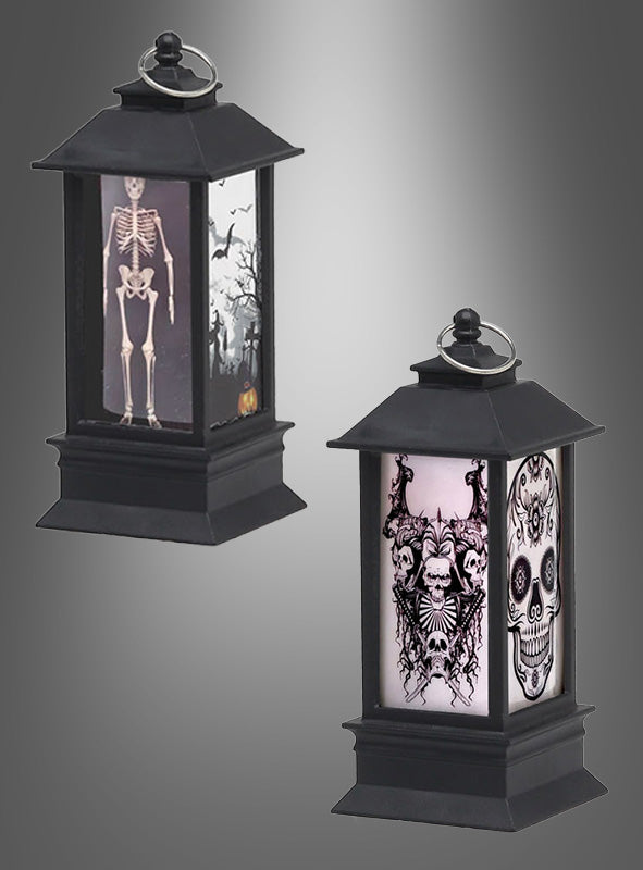 Zwei schwarze Halloween-Laternen (13 cm) mit Licht und Motiven zum Thema Halloween: Auf der einen ist ein Skelett zu sehen, das von Fledermäusen umgeben ist, während die andere einen Totenkopf mit filigranen Mustern sowie ein bedrohliches Skelett und Fledermäuse zeigt. Jede der 13 cm großen Halloween-Laternen mit Licht sorgt mit einem flackernden Kerzeneffekt für eine besonders gruselige Atmosphäre.