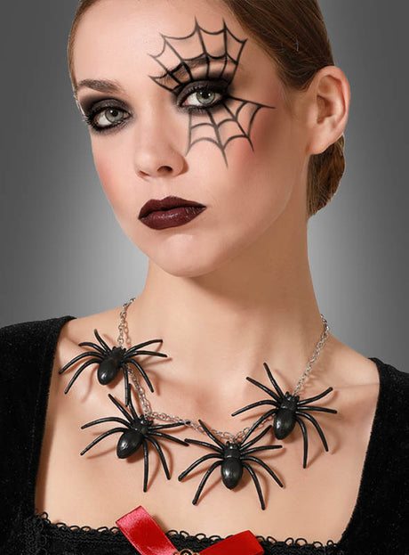 Eine Frau mit dunklem Make-up und einer Spinnennetz-Gesichtsbemalung über einem Auge trägt die „Spinnen-Halskette Halloween“ mit großen schwarzen Plastikspinnen vor grauem Hintergrund.