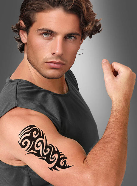 Ein Mann in einem ärmellosen Hemd spannt seinen rechten Arm an und präsentiert stolz das Tattoo-Abziehbild „Trible“ (9,5 x 18,5 cm) auf seinem Oberarm – ein markantes Beispiel für temporäre Körperkunst.