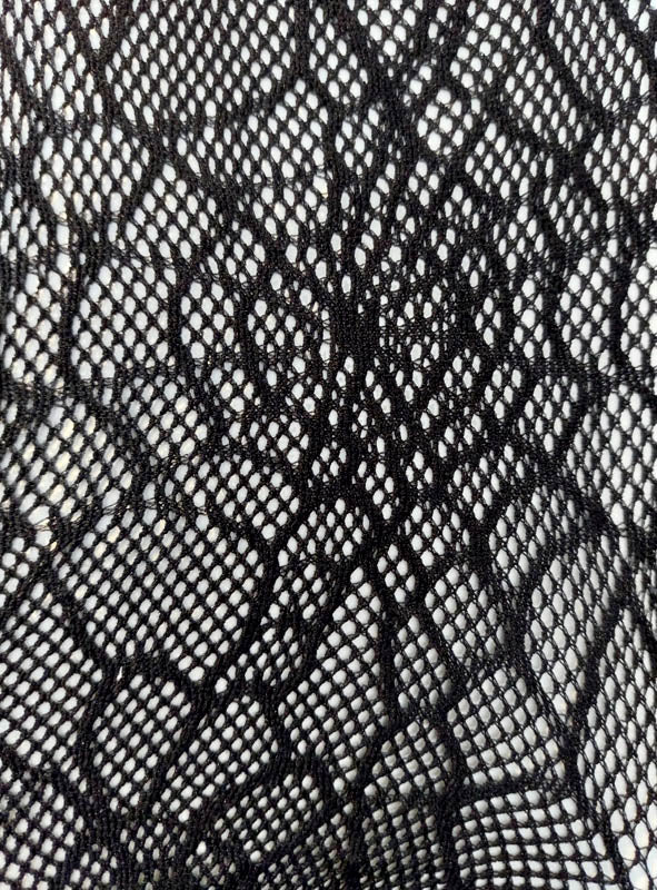 Nahaufnahme eines schwarzen Spitzenstoffs mit einem aufwendigen floralen und geometrischen Muster sowie feinen Netzdetails, inspiriert von der Netzstrumpfhose mit Spinnennetz-Muster – ideal, um jedem Halloween-Kostüm einen geheimnisvollen Touch zu verleihen oder als modische Hexenstrumpfhose zu tragen.