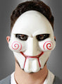 Eine Person, die die „Gruselige Maske Killer Puppe“ trägt – eine weiße Horror-Maske mit schwarzem Augen-Make-up, roten, spiralförmigen Wangen und roten Lippen, inspiriert von der Killerpuppe aus „Saw“.