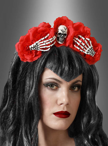 Eine Frau mit dunklem Haar trägt den Halloween-Haarreif mit Blumen und Skelett – ein rotes Blumenstirnband, das mit Skeletthänden und einem Totenkopf verziert ist. Ihr auffälliges Make-up mit dunklem Lidschatten und leuchtend rotem Lippenstift macht dieses Accessoire zum idealen Halloween-Accessoire, um dein „Día de los Muertos“-Kostüm zu vervollständigen – alles vor einem grauen Hintergrund mit Farbverlauf.