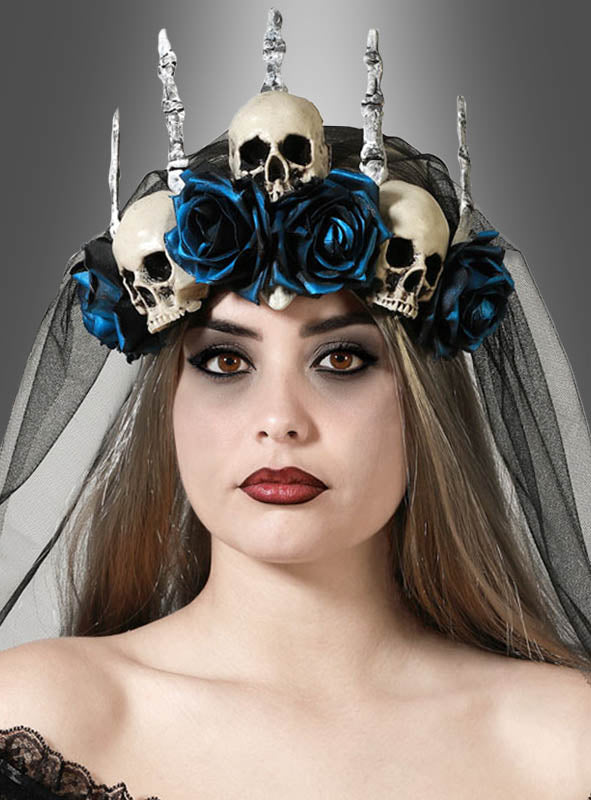 Eine Frau, die die „Halloween-Krone mit Schleier und blauen Rosen“ trägt – mit einem schwarzen Schleier, blauen Rosen, drei Totenköpfen und silbernen Stacheln –, steht vor einem neutralen Hintergrund.