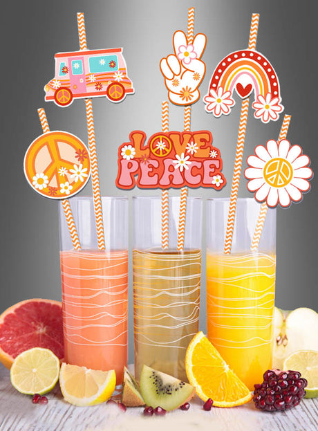 Drei Gläser Saft mit orange gestreiften Strohhalmen „Hippie Party“ (36 Stück) und farbenfrohen Dekorationen im Stil der 1960er Jahre. Vor den Gläsern sind Zitrusfrüchte und Granatapfelstücke angerichtet – perfekt für jede Hippie-Mottoparty.