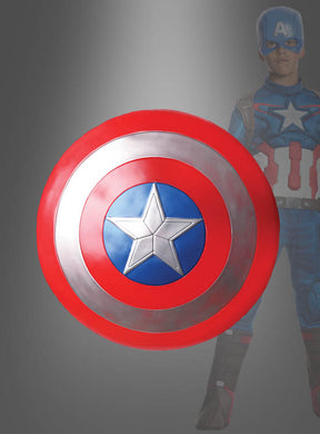 Ein kleines Captain-America-Schild (30 cm) dominiert den Vordergrund, während im Hintergrund teilweise eine Person im Superheldenkostüm von Captain America zu sehen ist.