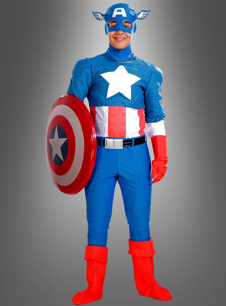 Eine Person trägt das Captain-America-Kostüm „Deluxe“ (2. Wahl) und hält ein rot-weiß-blaues Schild vor einem grauen Hintergrund mit Farbverlauf – das perfekte Marvel-Lizenzkostüm für jeden Superhelden-Fan.