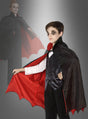 Ein Kind trägt den „Vampir-Umhang für Kinder“, einen schwarz-roten Umhang, der sich ideal für jedes Halloween-Kostüm oder jede Verkleidungsparty eignet, und posiert mit ausgestrecktem Arm; im Hintergrund rundet eine verblasste Gestalt eines Erwachsenen in einem passenden Vampirumhang die gruselige Szene ab.