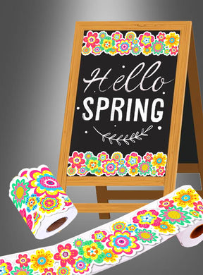Auf einem Kreidetafelschild steht „Hello Spring“ mit bunten Blumenrändern, was die fröhliche Stimmung der „Sommerfest Hippie Party Deko Aufkleber Rolle 20 m“ widerspiegelt. Vor dem Schild liegen dekoratives Toilettenpapier mit passenden Blumenmustern und verspielte Aufkleber von der 20-Meter-Rolle.