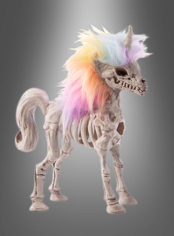 Vor einem grauen Hintergrund mit Farbverlauf steht das „Einhorn Skelett Deko 20 cm“ – eine Einhorn-Skelettfigur mit einer leuchtenden, regenbogenfarbenen Mähne –, die sich als echter Blickfang perfekt für Ihre Halloween-Dekokollektion eignet.