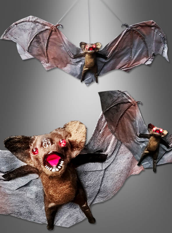 Drei riesige Fledermäuse (70 cm) mit leuchtenden Augen schweben mit weit ausgebreiteten Flügeln und geöffneten Mäulern vor einem grauen, verlaufenden Hintergrund.