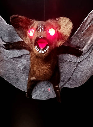 Die riesige Fledermaus (70 cm) mit leuchtenden Augen wird mit weit ausgebreiteten Flügeln und geöffnetem Maul vor dunklem Hintergrund präsentiert – ideal als gruselige Halloween-Dekoration.