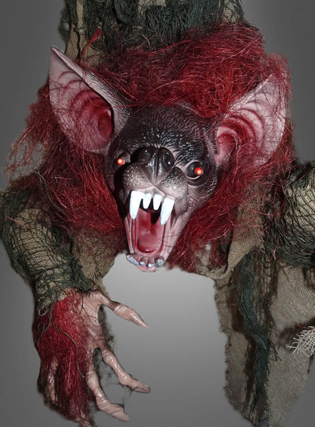 Die „Vampir-Fledermaus“-Dekoration mit LED, Sound und Bewegung (80 cm) zeigt eine Kreatur mit einem knurrenden, fledermausartigen Gesicht, großen Reißzähnen, spitzen Ohren, roten Augen, wildem rotem Haar und krallenbewehrten Händen vor einem neutralen Hintergrund.