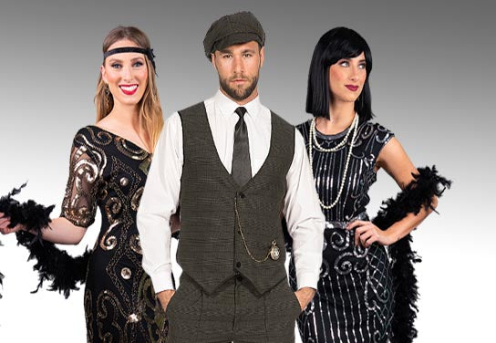 Drei Personen in von den 1920er Jahren inspirierten Outfits posieren gemeinsam; zwei Frauen tragen Flapper-Kleider und Federboas, während der Mann eine Weste, eine Krawatte und eine Schirmmütze trägt.