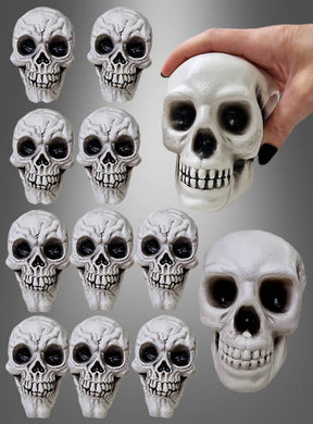 Ein Set aus 12 kleinen, grauen, strukturierten Totenkopf-Halloween-Dekorationsfiguren aus Kunststoff ist in einem Raster angeordnet, wobei oben rechts eine Hand eines der größeren Teile hält – perfekt für Ihre Halloween-Dekoration.