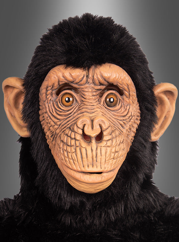 Vor einem neutralen grauen Hintergrund ist eine Person zu sehen, die die „Realistische Affenmaske für Erwachsene“ mit detaillierten Gesichtszügen und schwarzem Fell trägt. Diese hochwertige Latex-Affenmaske für Erwachsene fängt das lebensechte Wesen eines Schimpansen ein.