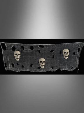 Das 300 cm lange Deko-Tuch mit Totenköpfen, gefertigt aus zerfetztem Mullstoff und verziert mit drei Totenköpfen, wird vor schwarzem Hintergrund gezeigt – perfekt als Halloween-Deko-Tuch, um Ihre gruselige Dekoration zu unterstreichen.