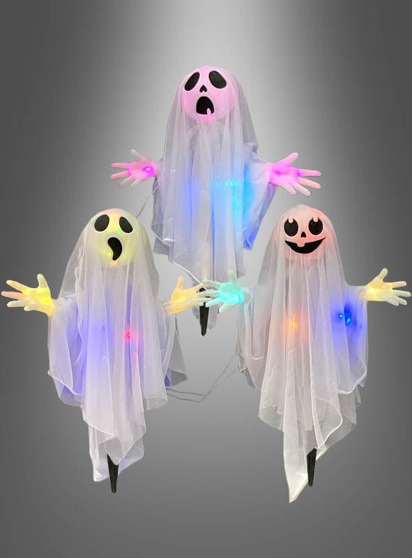 Drei „Geister Trio 60 cm“ – blinkende Halloween-Dekorationen aus transparentem Stoff mit ausdrucksstarken Gesichtern und leuchtenden, bunten LED-Lichtern – sind vor einem grauen Hintergrund zu sehen.