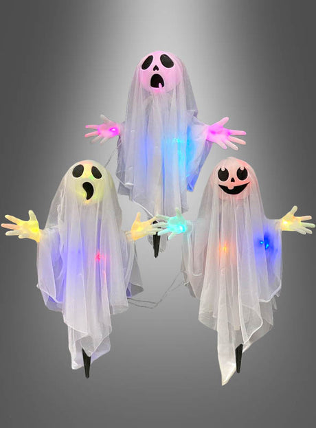 Drei „Geister Trio 60 cm“ – blinkende Halloween-Dekorationen aus transparentem Stoff mit ausdrucksstarken Gesichtern und leuchtenden, bunten LED-Lichtern – sind vor einem grauen Hintergrund zu sehen.