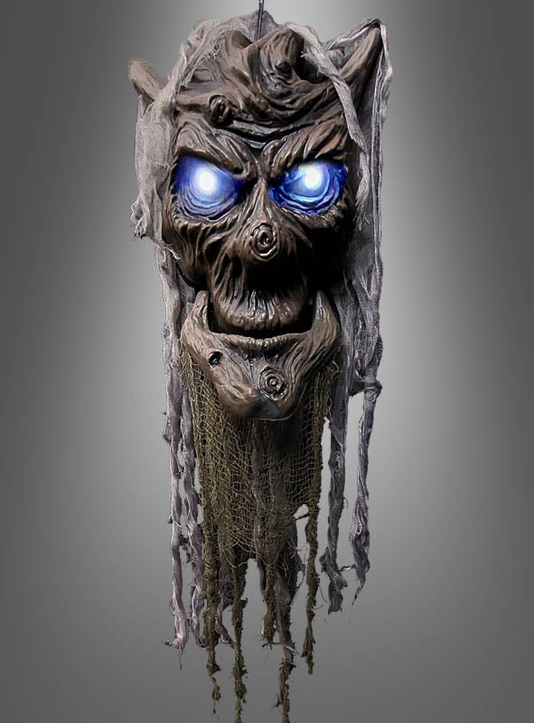 Ein furchteinflößender, verfallener „Sprechender Baumgeist animiert Halloween 85 cm“ mit leuchtend blauen Augen und zerfetztem grauen und braunen Stoff hängt vor einem schlichten grauen Hintergrund – ideal als einzigartige Halloween-Dekoration.