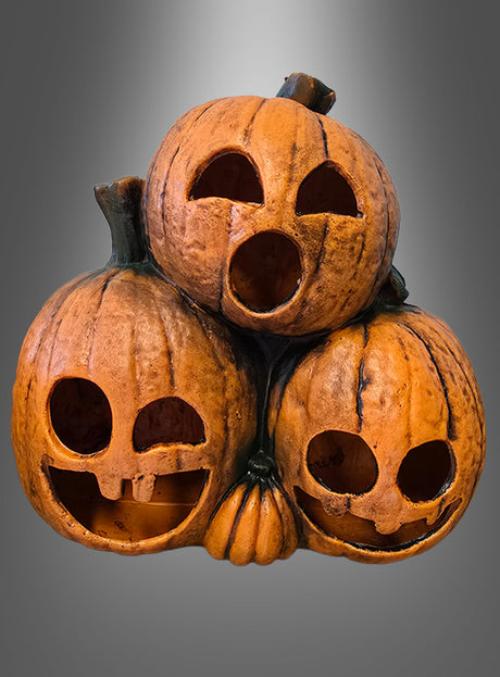 Drei geschnitzte Kürbisse mit unterschiedlichen Gesichtsausdrücken sind vor einem grauen Hintergrund mit Farbverlauf übereinander gestapelt – die bezaubernden „Kürbisgeister 29 cm mit LED“, perfekt als Halloween-Dekoration oder für alle, die auf der Suche nach einer Kürbisdekoration mit LED-Licht sind.