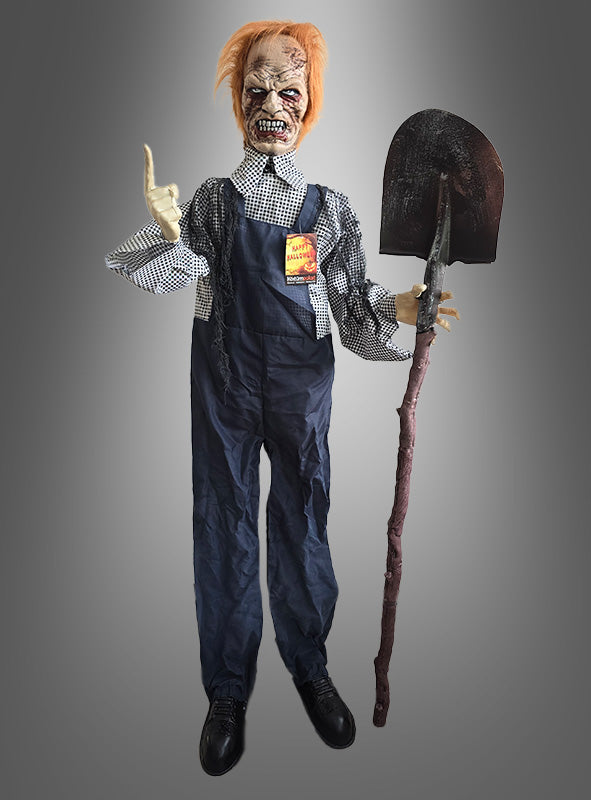 Die animierte Zombie-Totengräberfigur mit Schaufel (160 cm) trägt eine Zombie-Maske, ein kariertes Hemd und eine Latzhose, hält eine Schaufel in der Hand und zeigt mit einer Hand nach oben. Diese Halloween-Dekofigur steht vor einem grauen Farbverlaufshintergrund und sorgt so für eine unheimliche Atmosphäre – ideal für deine gruselige Dekoration.