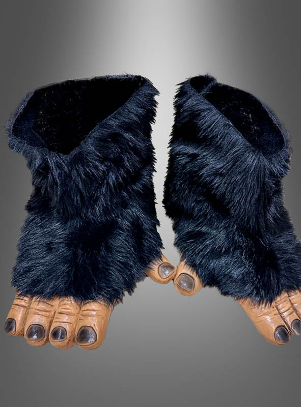 Ein Paar schwarze, pelzige Kostümfüße mit großen Zehen und Krallen, die Tier- oder Monsterfüßen nachempfunden sind, werden vor einem grauen Hintergrund mit Farbverlauf gezeigt – ideal als Schimpansenfüße für Affenkostüme für alle, die nach Affenfüßen für Erwachsene suchen oder ihr Urzeit-Outfit vervollständigen möchten.