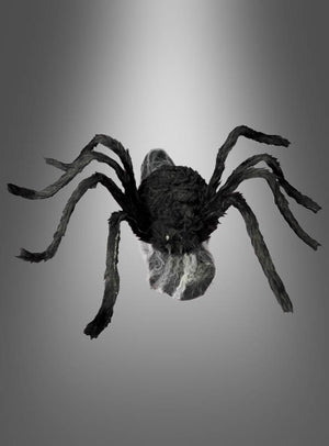 Eine springende Spinne (70 x 50 cm) in Schwarz mit acht Beinen und sichtbaren Fangzähnen wird vor einem grauen Farbverlauf präsentiert – ideal als Halloween-Dekoration oder für deine eigene Inszenierung mit einer animierten Riesenspinne.
