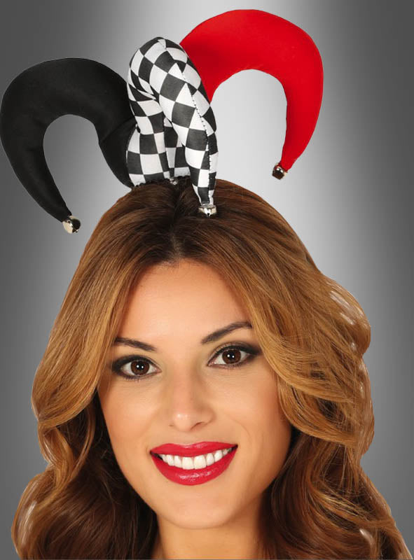 Eine Frau lächelt und trägt einen „Jester Clown“-Kopfschmuck mit Glöckchen, der schwarz-weiß kariert ist und rote Akzente aufweist, vor einem grauen Hintergrund mit Farbverlauf.