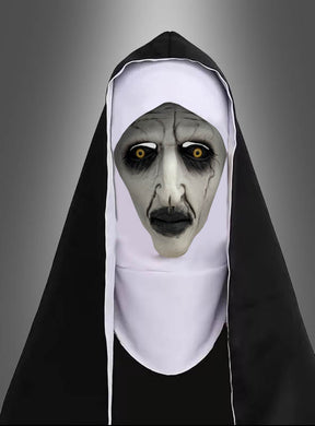 Eine Person, die als gruselige Nonne verkleidet ist – mit blasser Haut, schwarzen Lippen, dunklem Augen-Make-up und gelben Augen –, steht vor einem neutralen Hintergrund mit Farbverlauf und trägt eine schwarz-weiße Ordenskleidung sowie die „Horror Nonne Vollmaske“.