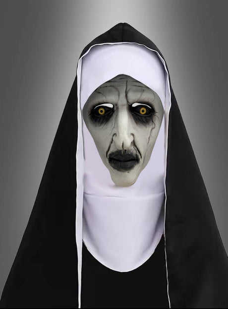 Eine Person, die als gruselige Nonne verkleidet ist – mit blasser Haut, schwarzen Lippen, dunklem Augen-Make-up und gelben Augen –, steht vor einem neutralen Hintergrund mit Farbverlauf und trägt eine schwarz-weiße Ordenskleidung sowie die „Horror Nonne Vollmaske“.