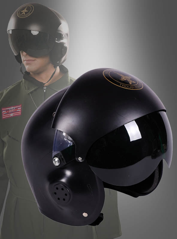 Im Vordergrund ist ein schwarzer Pilotenhelm für Erwachsene mit einem dunklen Doppelvisier zu sehen, während im Hintergrund eine Person in einem grünen Fluganzug einen weiteren Helm trägt, wodurch dessen modernes Jethelm-Design besonders hervorgehoben wird.