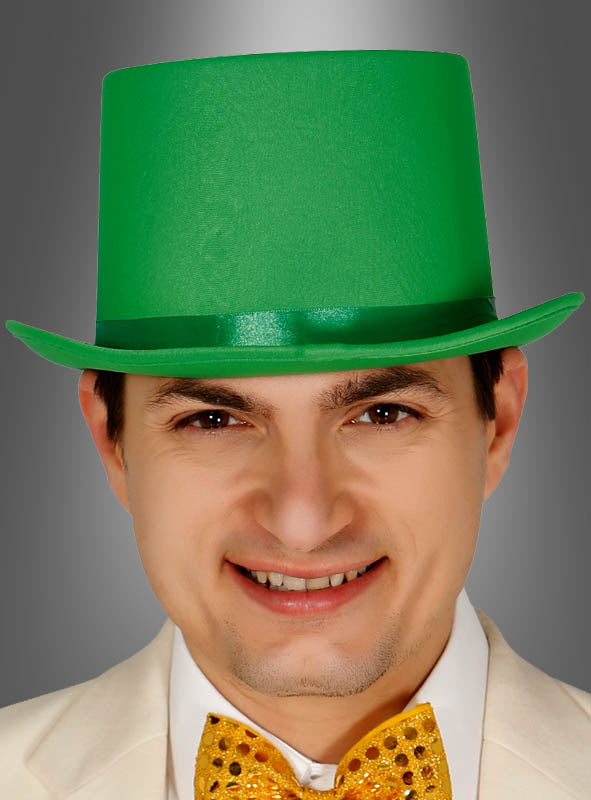 Ein Mann, der einen „Grüner Zylinder“-St.-Patrick’s-Day-Hut, ein weißes Sakko und eine goldene Pailletten-Fliege trägt, lächelt vor einem grauen Hintergrund.