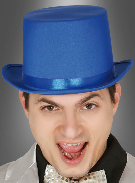 Vor einem grauen Hintergrund steht eine Person, die einen „Eleganter Zylinder Hut blau“ – einen glänzenden, blauen Zylinder – und eine funkelnde Fliege trägt, den Mund offen und die Augenbrauen hochgezogen.