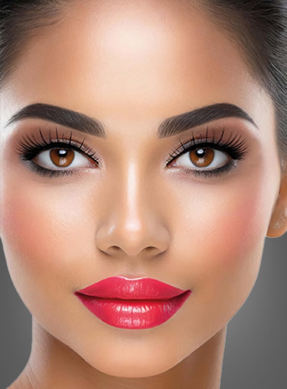 Nahaufnahme des Gesichts einer Frau mit glatter Haut, markanten Augenbrauen, langen Wimpern, die durch selbstklebende „Glamour“-Kunstwimpern betont werden, braunen Augen, rosa Rouge und rotem Lippenstift.