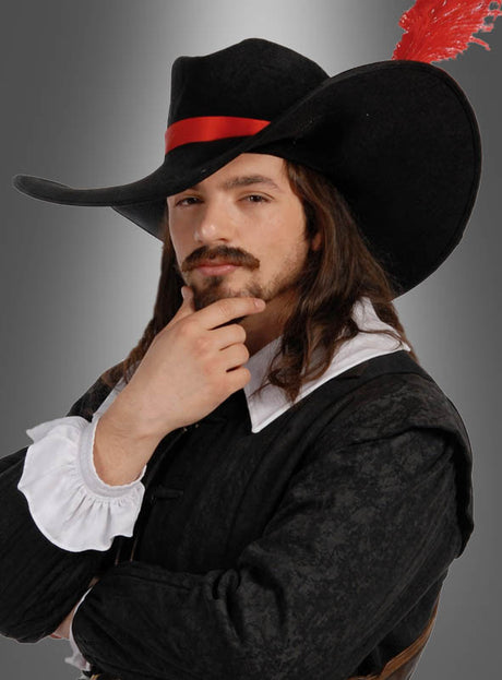 Ein Mann mit langen braunen Haaren und einem Schnurrbart trägt einen schwarzen „Cavalier Hut für Musketier-Kostüme“, der mit einer roten Feder verziert ist, sowie ein schwarz-weißes Kostüm im historischen Stil – damit ist er das perfekte, auffällige Accessoire für jedes Musketier-Kostüm.