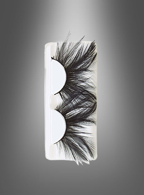 Ein Paar auffällige „Schwarze Wimpern mit Federn, selbstklebend“ in einer durchsichtigen Kunststoffhülle, präsentiert vor einem grauen Hintergrund mit Farbverlauf – diese „Fantasy Wimpern“ verleihen jedem Look einen bezaubernden Touch.