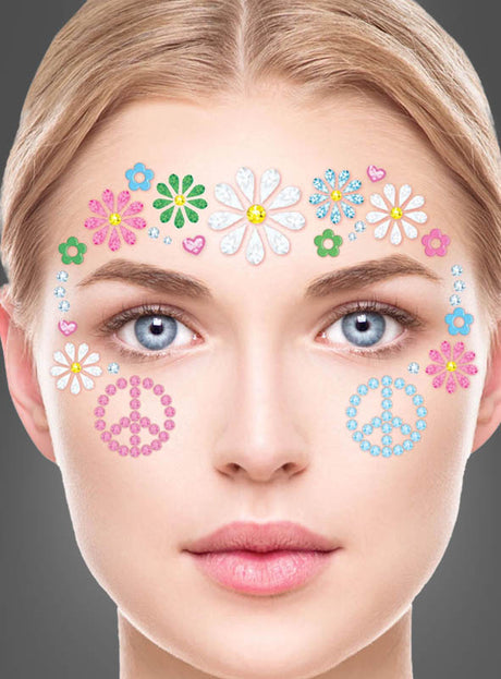 Eine Frau mit blauen Augen trägt „Hippie Strasssteine fürs Gesicht, selbstklebend“ – bunte Blumenaufkleber auf Stirn und Wangen, kombiniert mit rosa Peace-Zeichen-Aufklebern auf jeder Wange –, die den lebhaften Flower-Power-Look perfekt einfangen. Vor einem grauen Hintergrund blickt sie direkt in die Kamera und verkörpert dabei den wahren Hippie-Spirit.