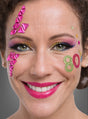 Eine Frau mit auffälligem Make-up, rosa Lippenstift und bunten 80er-Jahre-Schmuck-Tattoo-Glitzersteinen im Gesicht, darunter die Zahl „80“ und geometrische Formen – ein auffälliger Look, inspiriert von den lebhaften Tattoo-Trends der 1980er Jahre und dem Flair von Retro-Accessoires.