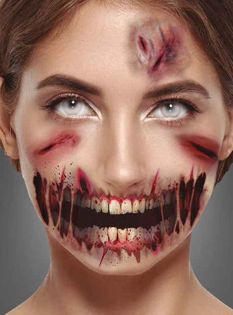 Eine Frau mit realistisch wirkendem Spezialeffekt-Make-up zeigt blutige Wunden an Stirn und Wangen sowie einen aufgerissenen Mund, aus dem Zähne hervorschauen – die ideale Inspiration für das „Schürfwunden-Tattoo mit aufgerissenem Mund“ oder temporäre Tattoos zu Halloween. Grauer Hintergrund.